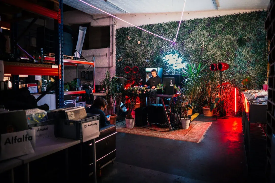 csm records session Einblick ins CSM Lager mit DJ-Setup, Plattenkisten, Pflanzen und roten Void-Lautsprechern.